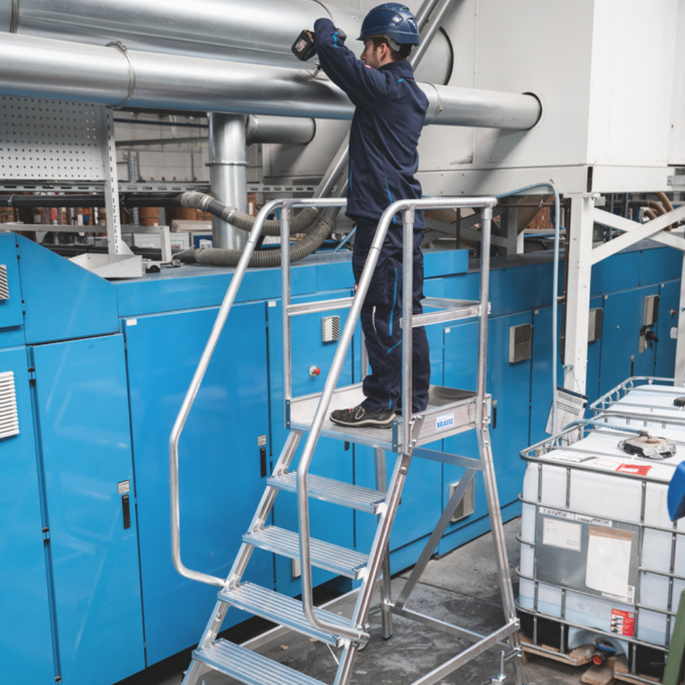 Trabalhador em escadote com plataforma de alumínio a realizar manutenção industrial