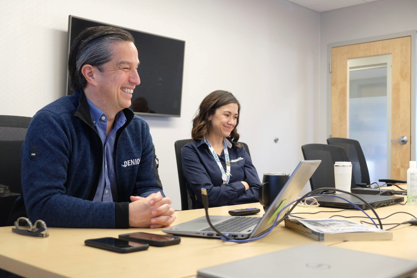 two denios employees smiling in a meeting