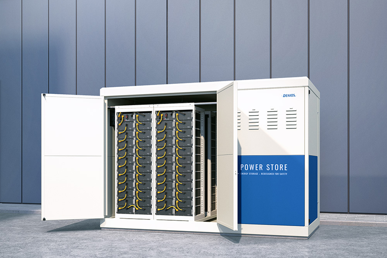 Egy modern energiatároló egység nyitott ajtókkal, amelyeken több akkumulátorállvány látható, egy elegáns ipari épület hátterében, kék ég alatt.