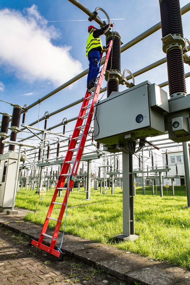 Trabalhador a realizar manutenção elétrica em subestação usando escada de plástico reforçado com fibra de vidro isolante