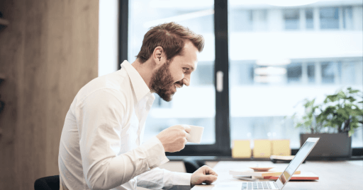 Forretningsmann drikker kaffe og får online coaching på datamaskinen sin