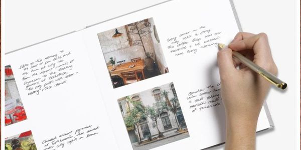 Eine Hand schreibt mit einem Stift in ein YAY-Fotobuch