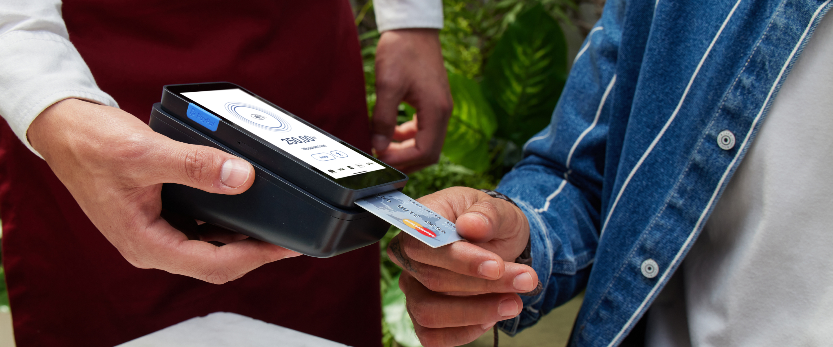 Waiter at a restaurant holding a PayPal Terminal for a customer to insert a credit card for payment