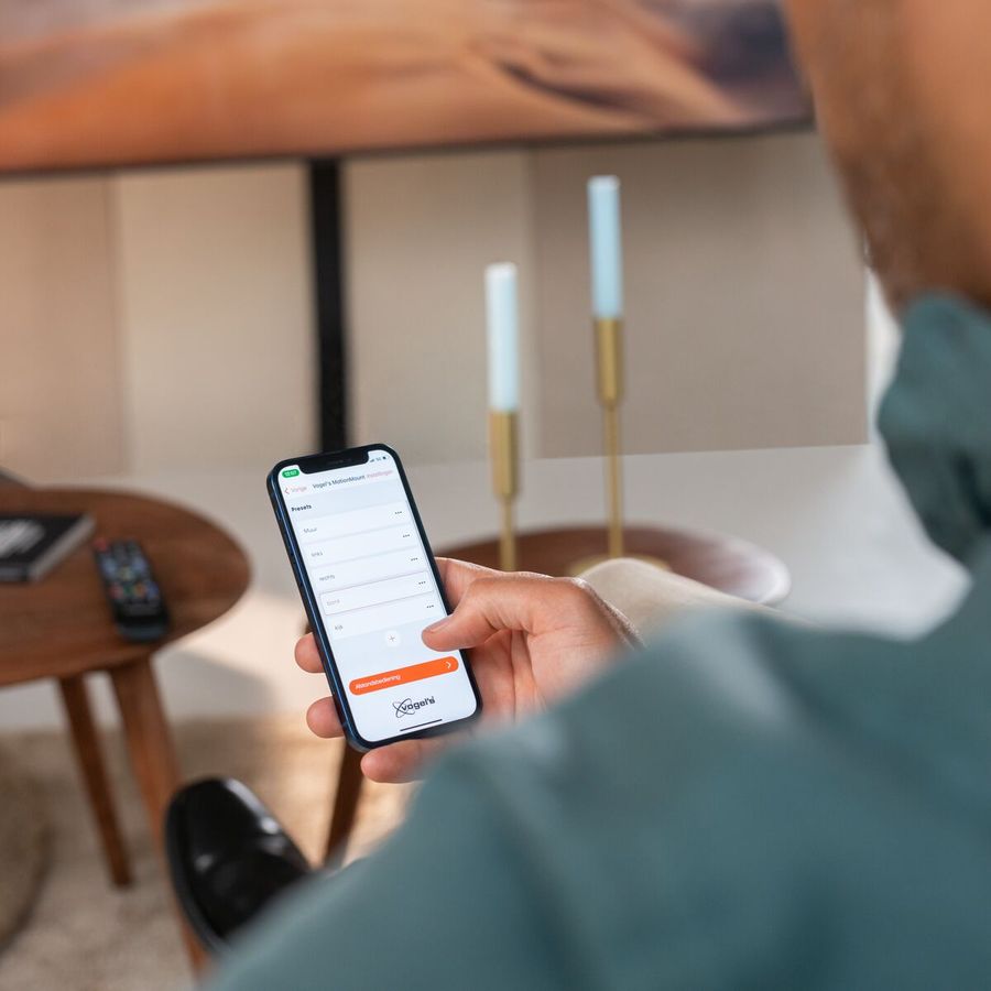Man gebruikt MotionMount app voor gemotoriseerde TV muurbeugel | Vogel's