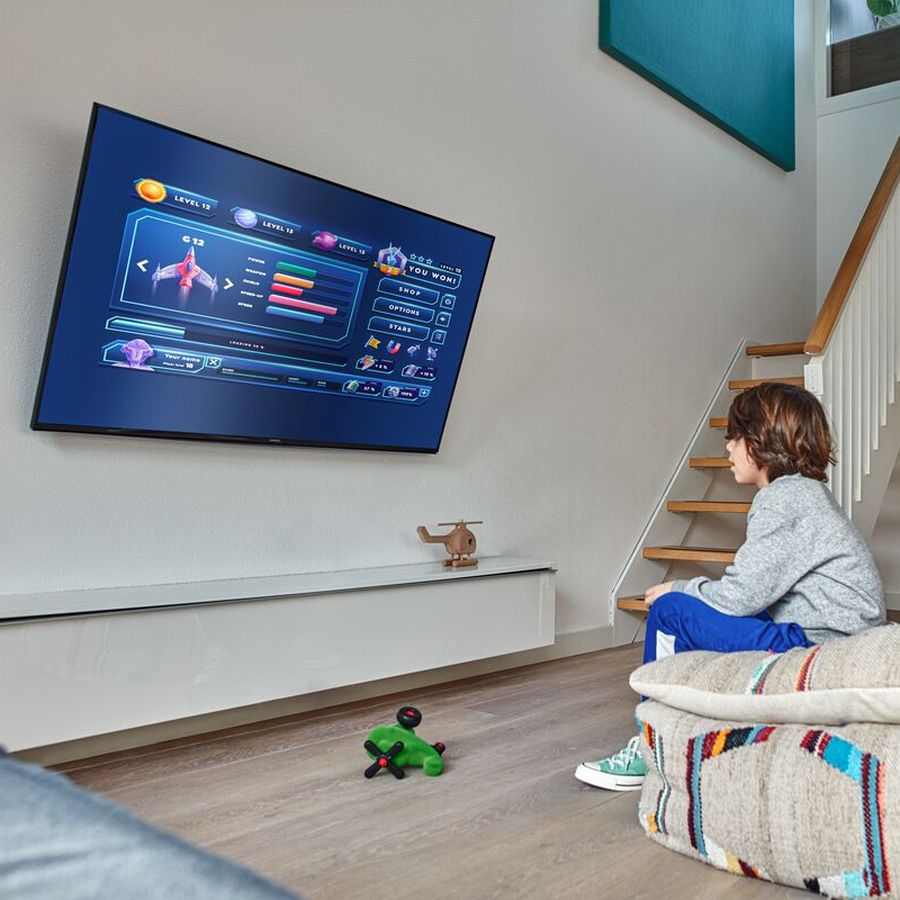 Little boy gaming in front of the TV mounted safely, COMFORT | Vogel's