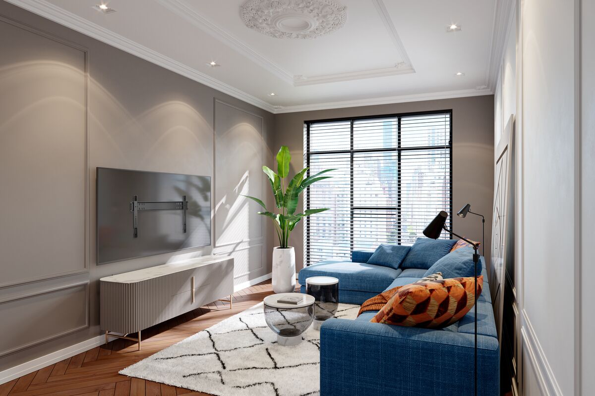 Modern living room with a blue sectional sofa, decorative pillows, a large plant, wall-mounted TV 5705, and a patterned rug on wooden flooring.
