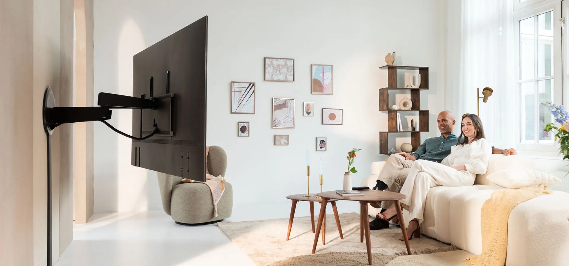 Motorized TV Wall bracket in livingroom with couple on the couch | Vogel's 