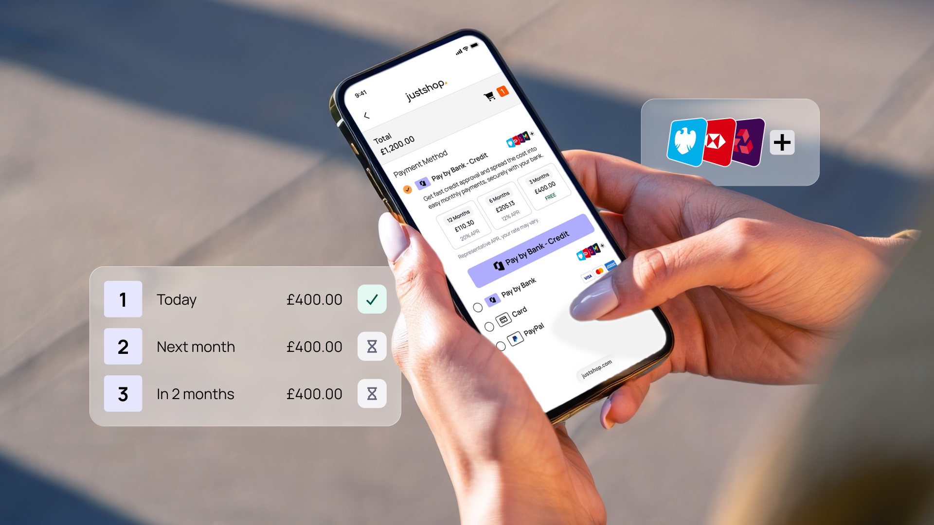 Hands holding a smartphone displaying a payment screen from "justshop" with bank options and installment payment plan details.