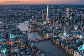 Aerial view of London's skyline at dusk, featuring the Thames River, illuminated buildings, and iconic skyscrapers like The Shard.