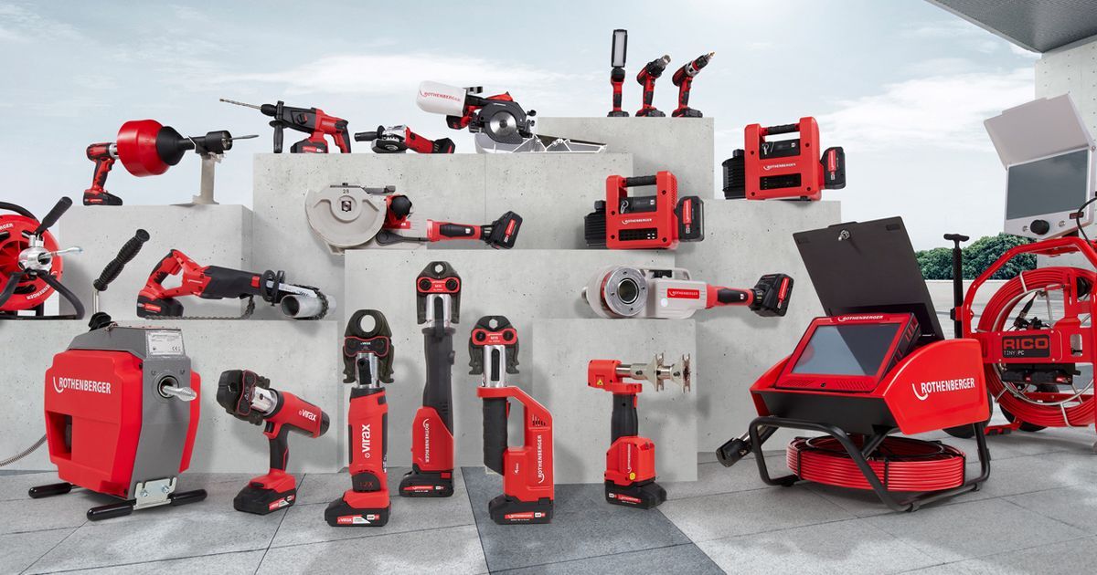 Various red and black construction tools displayed on tiered concrete platforms, including drills, saws, and pipe cutters, against a white wall.