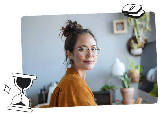 A woman with glasses and a bun sits at a desk, smiling slightly, with plants and decor in the background.