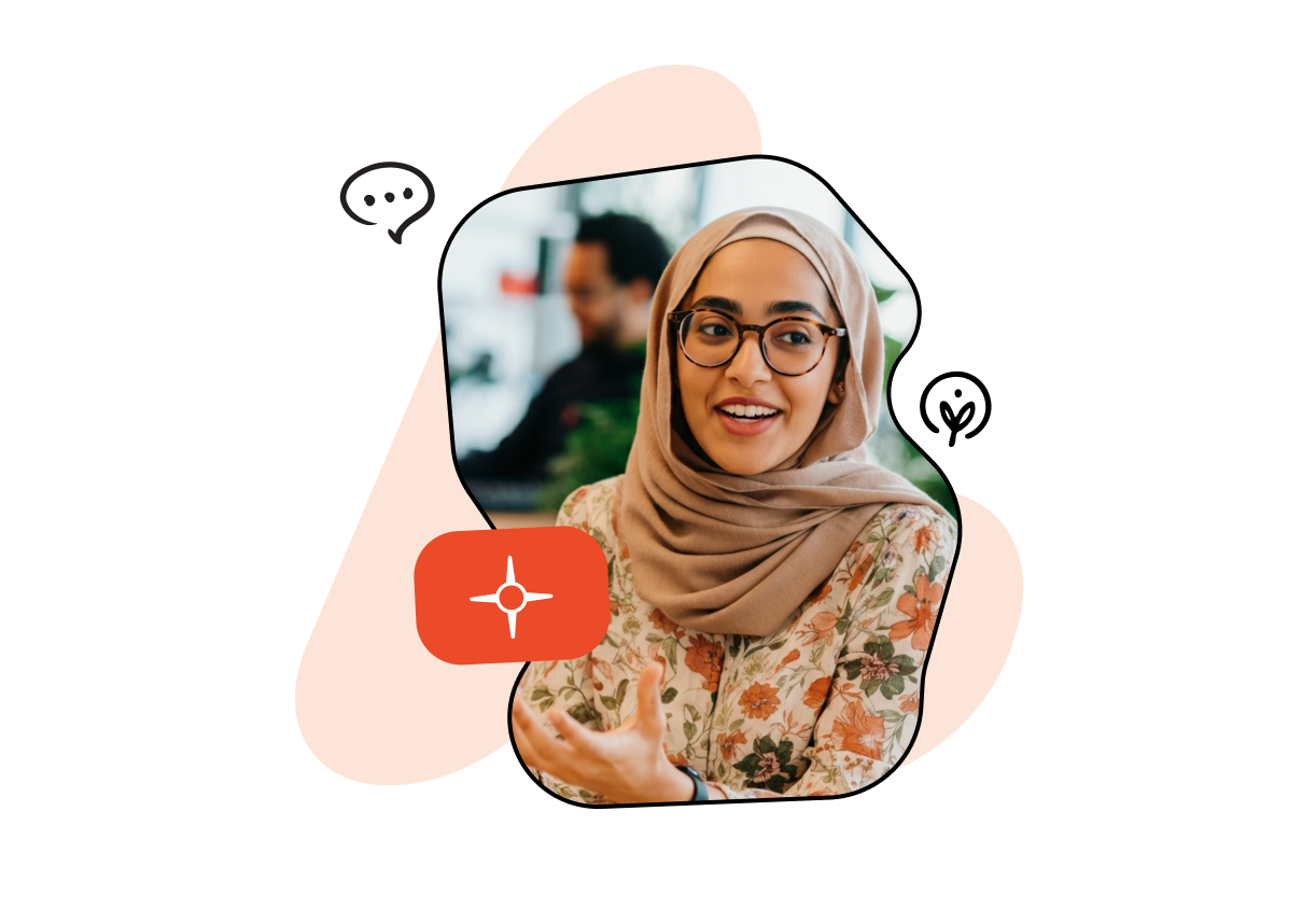 Smiling woman in a floral hijab and glasses gestures while speaking, with a blurred person in the background and a speech bubble icon nearby.