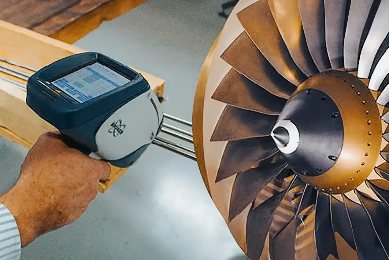A person uses a handheld device to inspect a turbine blade, highlighting the intricate metal design and engineering details.