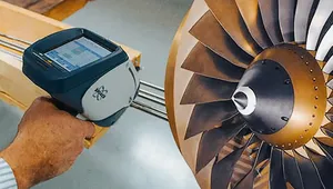A person uses a handheld device to inspect a turbine blade, highlighting the intricate metal design and engineering details.