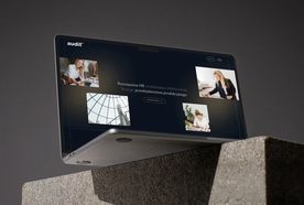 A laptop with a screen displaying a website titled "Audit." The background is gray, and the laptop is positioned on a concrete surface.