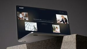 A laptop with a screen displaying a website titled "Audit." The background is gray, and the laptop is positioned on a concrete surface.