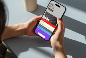 Person holding a smartphone displaying a colorful menu screen titled "ONS WERK," with several navigation options visible.