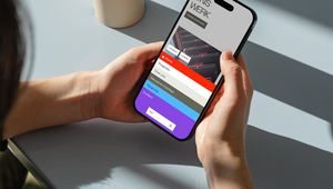 Person holding a smartphone displaying a colorful menu screen titled "ONS WERK," with several navigation options visible.