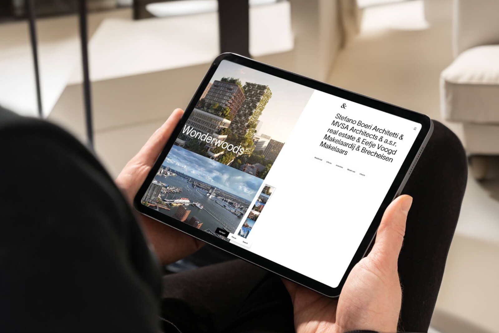 Person holding a tablet displaying architectural project "Wonderwoods" with images of cityscapes and text detailing architects and real estate partners.