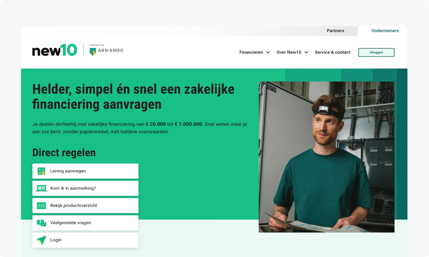 A man stands in an office with papers in hand, beside a sign offering business financing from €20,000 to €1,000,000 with direct processing options.