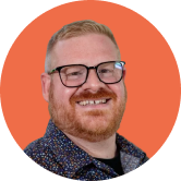 Smiling man with glasses and a beard, wearing a patterned shirt against an orange circular background.