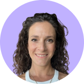 Smiling person with curly hair against a purple background, wearing a white top.