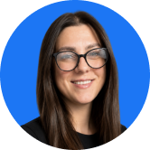 A person with long dark hair and glasses smiles, set against a solid blue background.