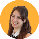 Young woman smiling, with long brown hair, wearing a sleeveless black top and white collar, against an orange background.