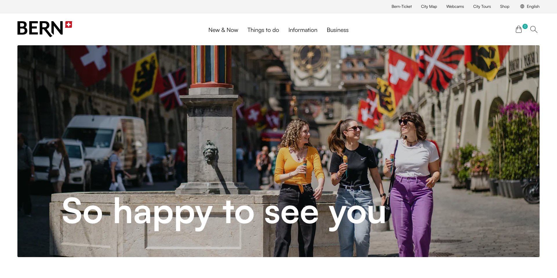 Three women walking and eating ice cream in a lively street in Bern, Switzerland, with flags and a clock tower in the background.