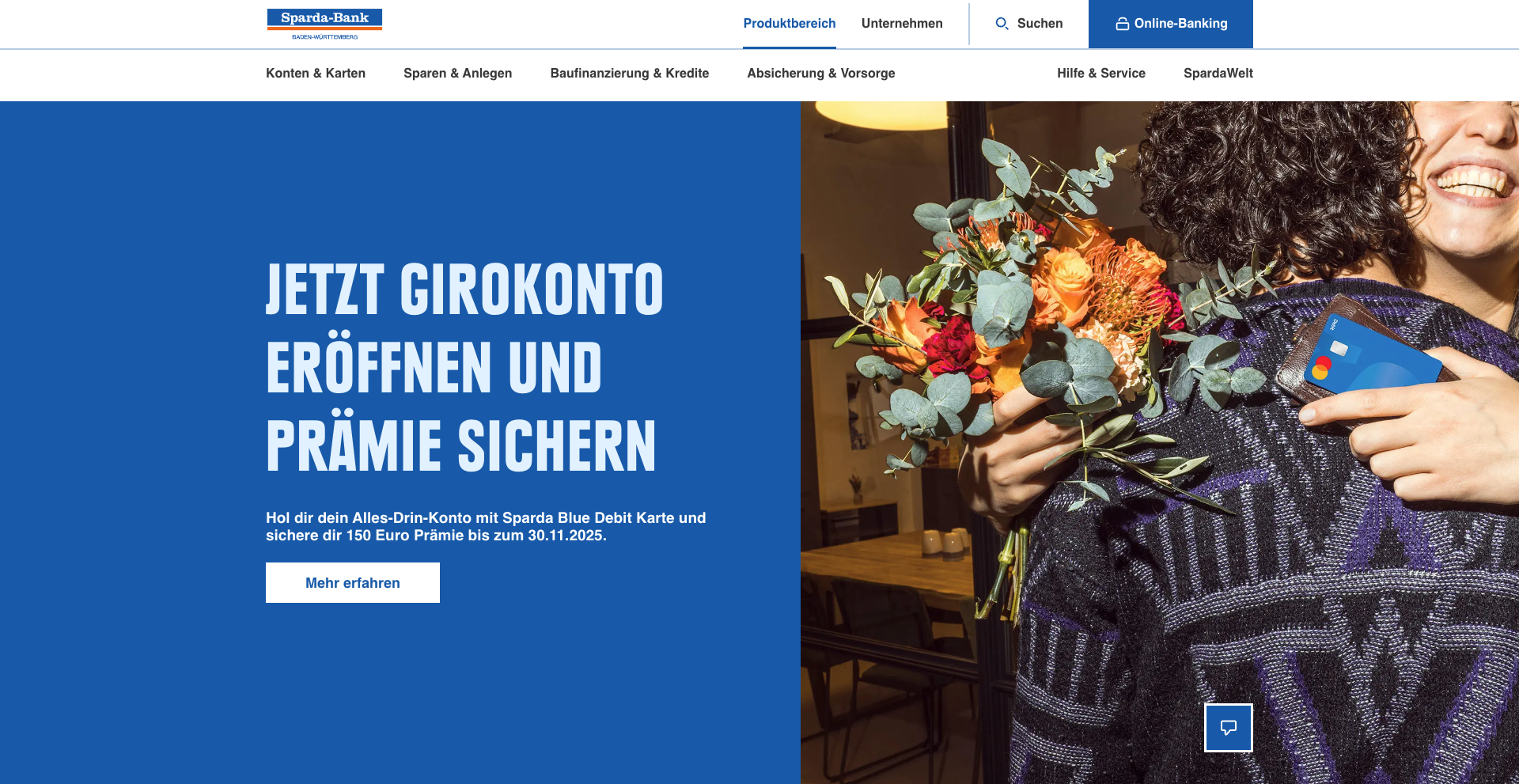 Homepage banner of the Sparda-Bank Baden-Württemberg website. On the left, a solid blue panel displays the headline “Jetzt Girokonto eröffnen und Prämie sichern” with a subtext promoting a €150 bonus for opening an account with the Sparda Blue Debit Card, along with a white “Mehr erfahren” button. On the right, a joyful person hugs someone while holding a bouquet of flowers and a blue debit card. The top navigation menu includes sections such as Konten & Karten, Sparen & Anlegen, Baufinanzierung & Kredite, Absicherung & Vorsorge, Hilfe & Service, and SpardaWelt, with links for Suchen and Online-Banking.