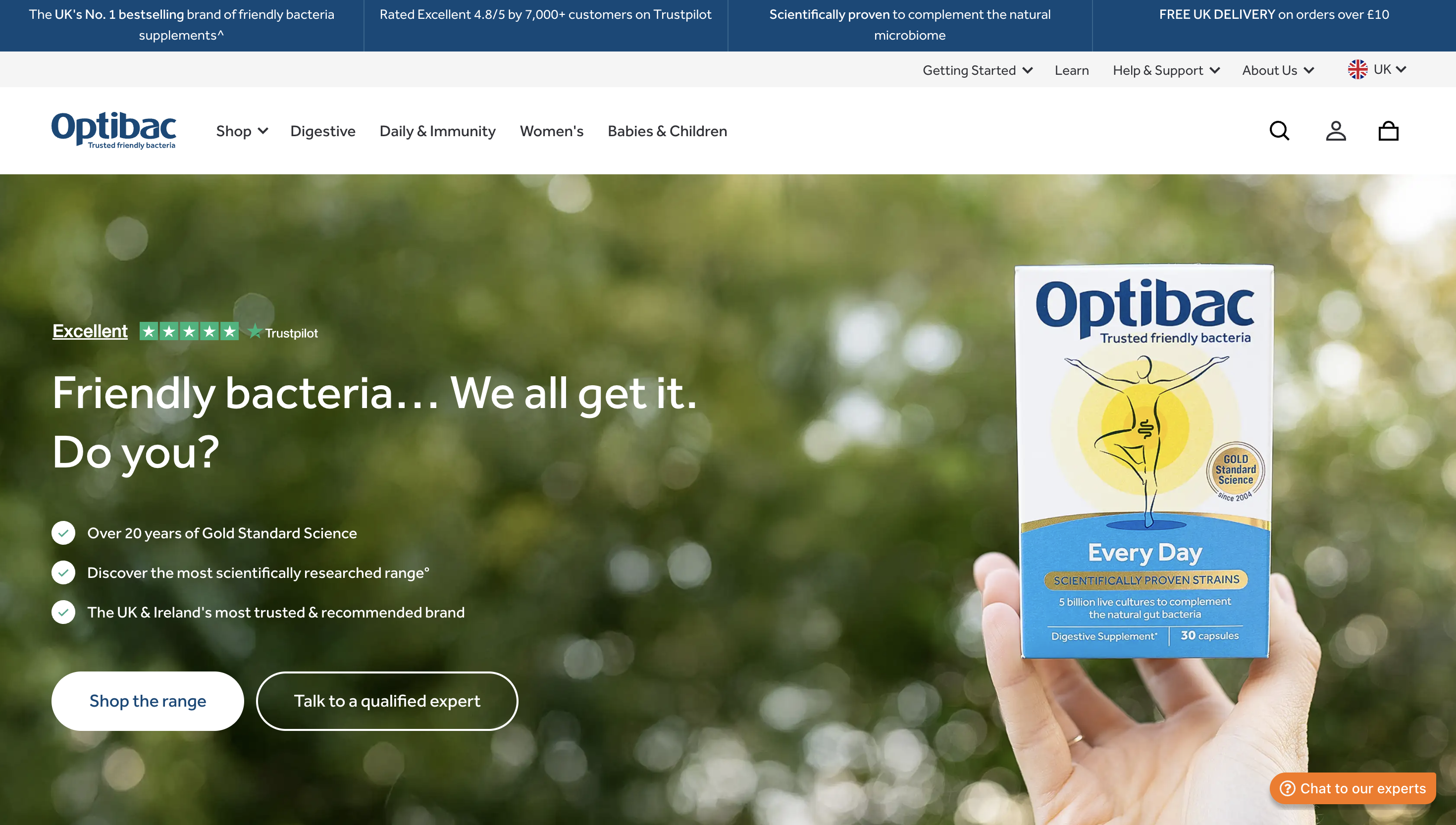 Hand holding a box of Optibac "Every Day" friendly bacteria supplement against a blurred green background, promoting gut health.