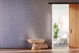 Modern room with patterned wallpaper, a potted plant, a wooden side table, and a sliding wooden door opening to a bright space with pendant lights.