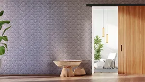 Modern room with patterned wallpaper, a potted plant, a wooden side table, and a sliding wooden door opening to a bright space with pendant lights.