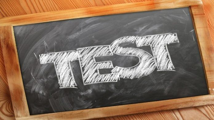 Chalkboard with the word "TEST" written in large, bold white letters, set against a wooden background.