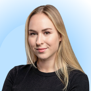Smiling person with long blonde hair in a black top against a gradient blue background.
