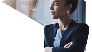 A woman in business attire stands with her arms crossed, looking thoughtfully out of a window. Her reflection is visible in the glass, and the image is framed within a geometric diamond-shaped overlay with a teal dot accent.