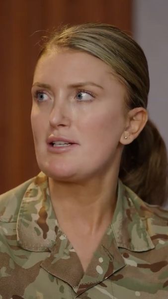 Person in a camouflage military uniform, looking to the side with a focused expression.