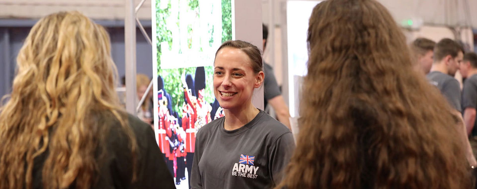 Female soldier talking to a couple of girls at an event