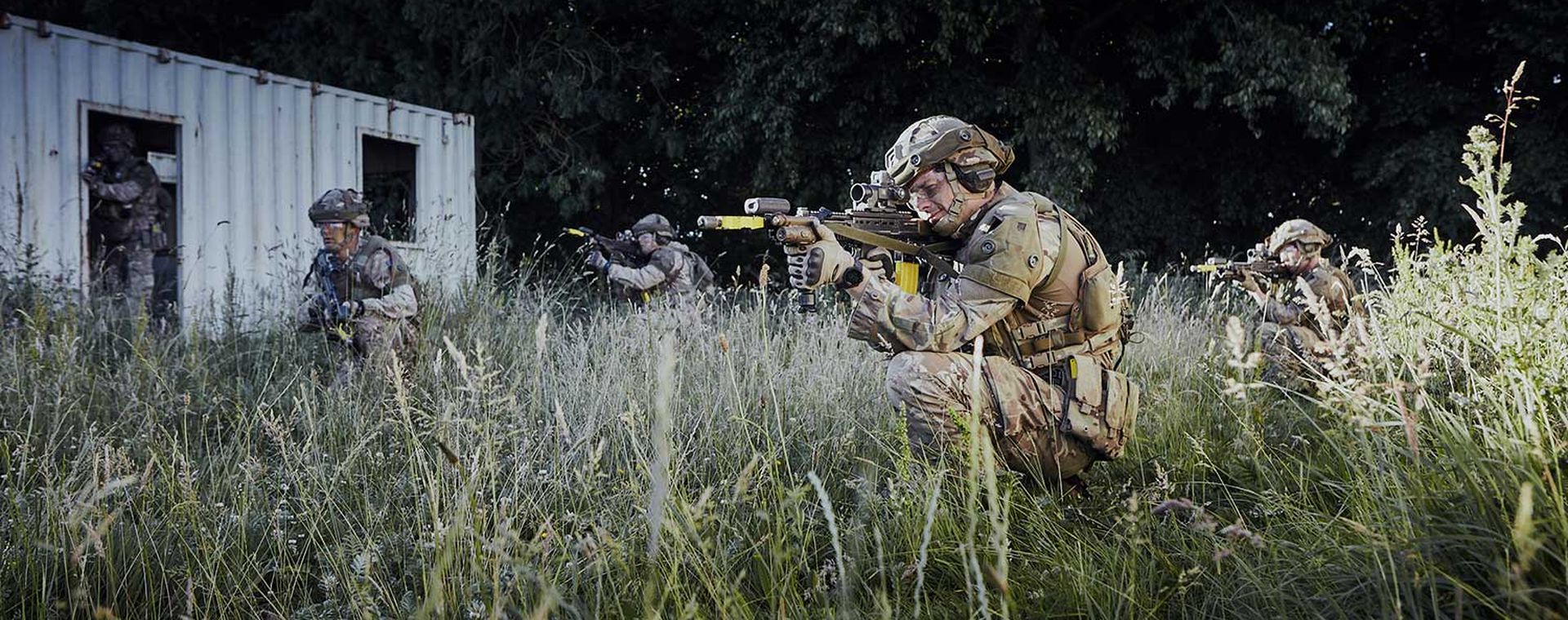 Soldiers in long grass aiming their rifles
