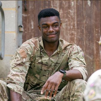 Soldier sitting on steps smiling and relaxing with a colleague