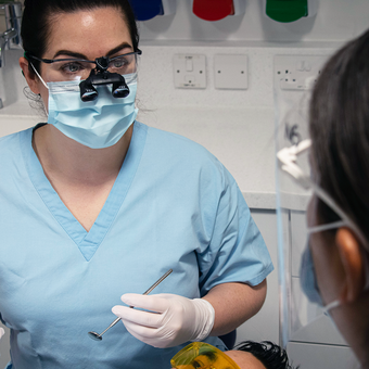 female dentist in blue scrubs treating a patient