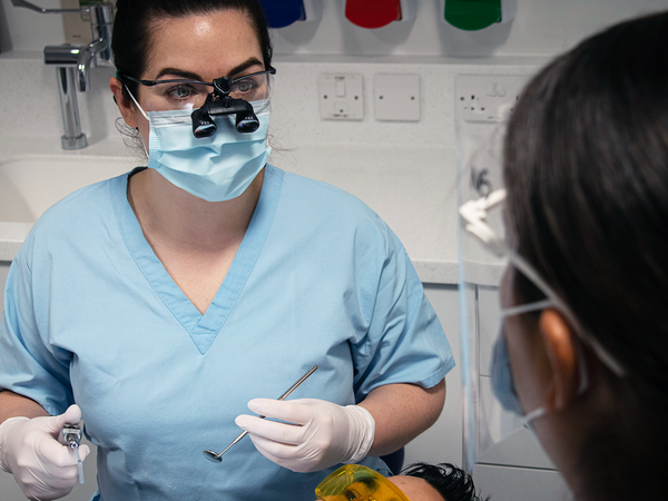 female dentist in blue scrubs treating a patient