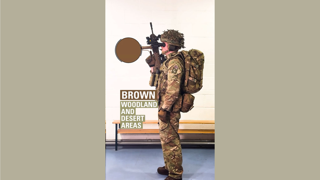 Video still of soldier in full camo, kit and gun and a pointer highlighting the brown colour