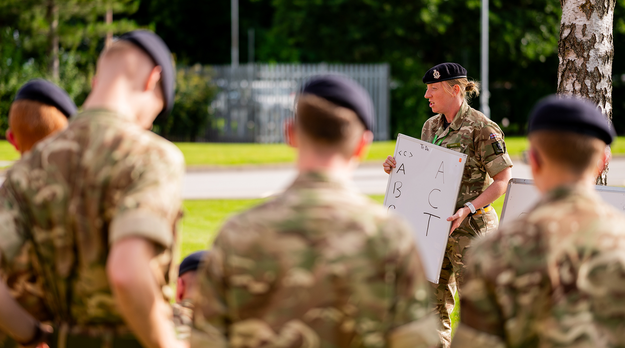 Junior soldiers outside listening to briefing by a superior