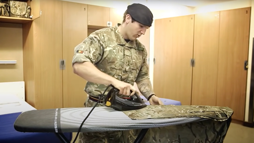 Soldier ironing a shirt in his room
