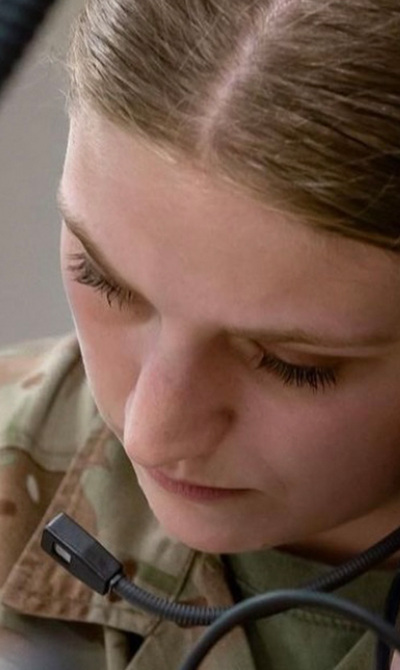 Female soldier closeup listening to something on a headset and writing it down