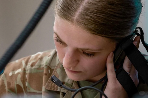 Female soldier closeup listening to something on a headset and writing it down