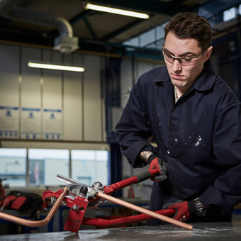Soldier in workshop working on a copper pipe