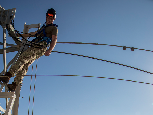 Soldier in climbing harness up a structure