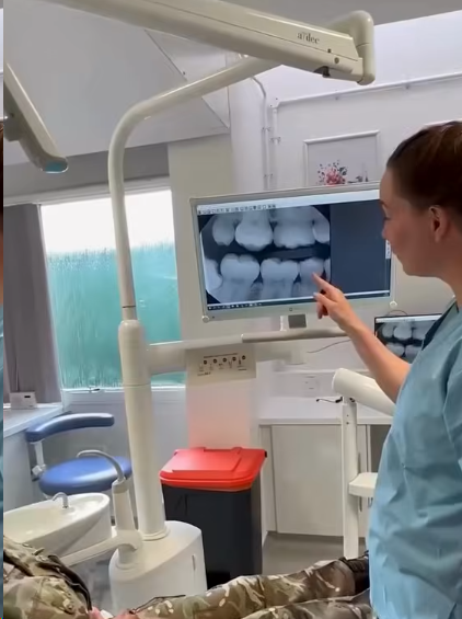 Dentist reviews dental X-rays on a monitor with a patient in a clinic.